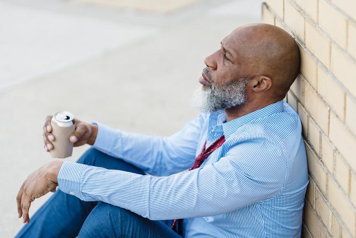 man sitting on ground holding soda can